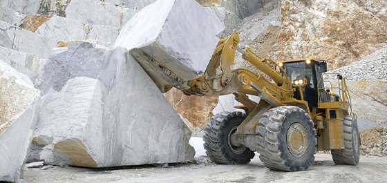 image of a backhoe lifting a large piece of rubble