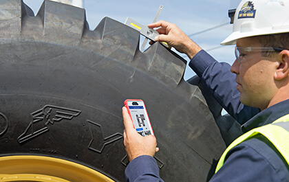 Person measuring tread depth of OTR tire